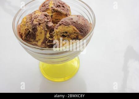 Kugeln Orange und Schokolade Eis in einem Glas Dessert Schüssel auf weißem Hintergrund mit Kopierraum. Selektiver Fokus Stockfoto