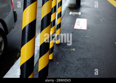 Gelbe und schwarze Sicherheitswarnstreifen von Hochspannungsmast auf dem Fußweg. Stockfoto