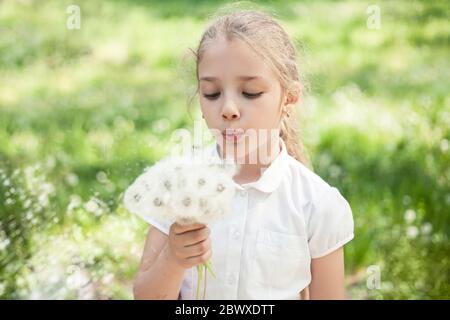 Ein Mädchen im Vorschulalter oder Grundschulalter mit Löwenzahn in der Hand auf einer Sommerwiese. Stockfoto