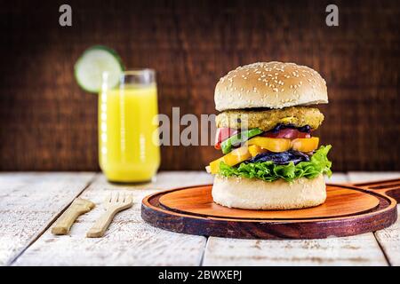 Veganer Hamburger, Sandwich ohne Fleisch, mit einem Glas grünen Saft im Hintergrund. Sandwich mit Pfeffer, Pilz, Tomaten, Salat und Eiweiß Stockfoto