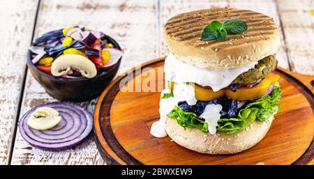 Amerikanischer veganer Hamburger, glutenfrei, Sandwich ohne Fleisch und weiße Sauce mit Kräutern. Sandwich mit Pfeffer, Pilz, Tomaten, Salat und Prot Stockfoto