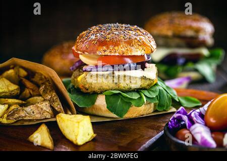 Veganer Hamburger, Sandwich ohne Fleisch, mit einem Glas grünen Saft im Hintergrund. Sandwich mit Pfeffer, Pilz, Tomaten, Salat und Eiweiß Stockfoto