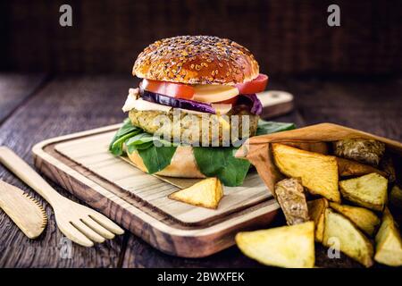 Vegetarischer Hamburger, Sandwich ohne Fleisch, mit recyceltem Bambus-Besteck. Sandwich mit Rucola-Salat, rote Zwiebel, Tomaten und Pilzen. Portion o Stockfoto