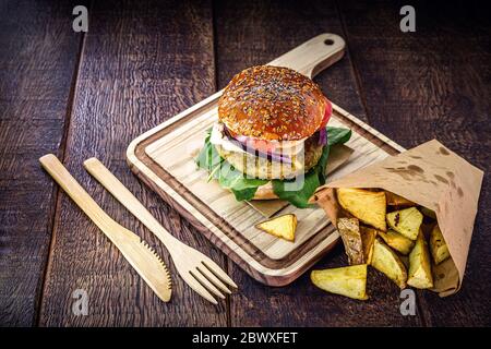 Vegetarischer Hamburger, Sandwich ohne Fleisch, mit recyceltem Bambus-Besteck. Sandwich mit Rucola-Salat, rote Zwiebel, Tomaten und Pilzen. Portion o Stockfoto