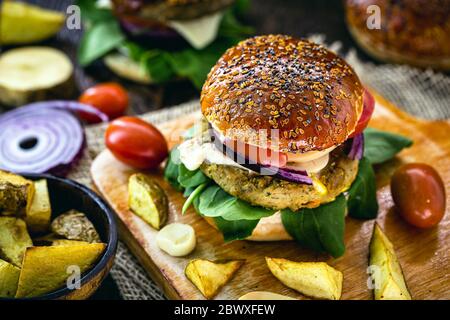 Veganer Hamburger, Sandwich ohne Fleisch, mit einem Glas grünen Saft im Hintergrund. Sandwich mit Pfeffer, Pilz, Tomaten, Salat und Eiweiß Stockfoto