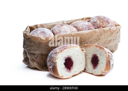 Frisch gebackene Donuts gefüllt mit Erdbeermarmelade in Papiertüte isoliert auf weiß Stockfoto