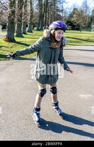 Ein dreizehn Jahre altes Mädchen, das im Park in London an Rollerblades praktiziert Stockfoto