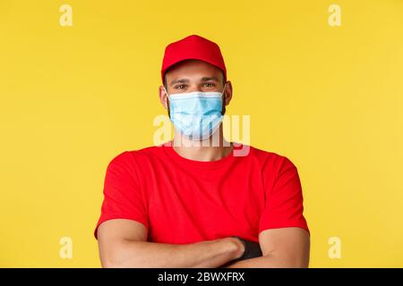 Covid-19, Lieferaufträge, Shopping, kontaktloses Bezahlen und soziales Distanzierungskonzept. Nahaufnahme eines sorglosen, gutaussehenden Kuriers, der optimistisch aussieht Stockfoto