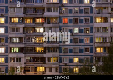 Fassade eines großen mehrstöckigen Wohnblocks mit vielen hellen Lichtfenstern in Wohnungen und Balkonen? Blick auf den Abend. Moskau Russland Stockfoto