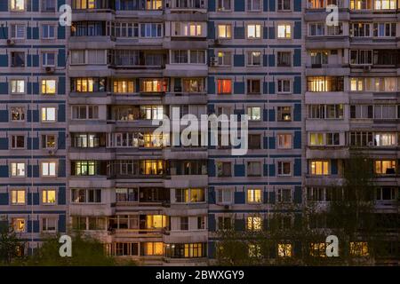 Fassade eines großen mehrstöckigen Wohnblocks mit vielen hellen Lichtfenstern in Wohnungen und Balkonen? Blick auf den Abend. Moskau Russland Stockfoto