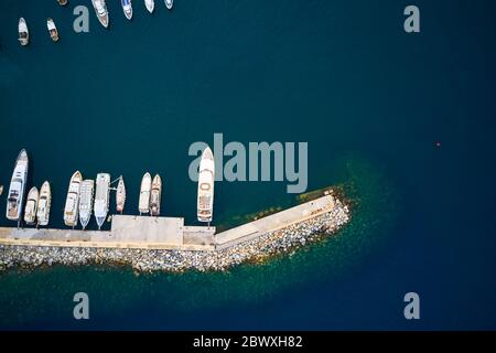 Blick von oben auf einen Hafen mit vertäuten Yachten, Booten und Schiffen im dunklen Meerwasser. Stockfoto