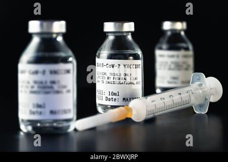 Coronavirus Covid-19 Impfstoff Konzept - drei Glasfläschchen auf schwarzem Tisch, hypodermische Spritze nahe Nahaufnahme Detail (Label eigenes Design - Dummy Daten, nicht r Stockfoto
