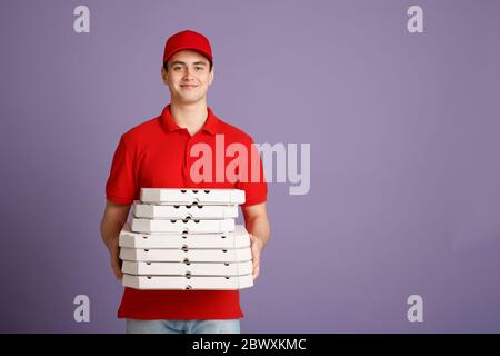Eine Menge Pizza für große Unternehmen. Lächelnder Kurier hält viele Kisten Stockfoto