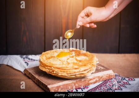 Frau gießt Honig auf Pfannkuchen, Hände Nahaufnahme, nach Hause. Stockfoto