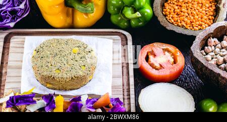 Roher veganer Burger, vor dem Braten. Aufgetauftes Fleisch, mit viel Gemüse herum. Tomate, ​​onion, Paprika, Rotkohl. Stockfoto