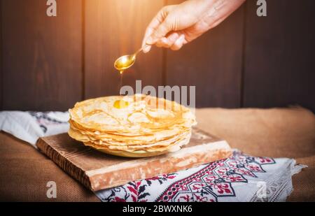 Frau gießt Honig auf Pfannkuchen, Hände Nahaufnahme, nach Hause. Stockfoto