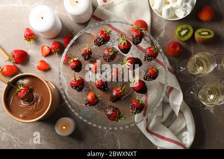 Komposition mit Schokoladenfondue auf grauem Tisch. Leckeres süßes Essen Stockfoto