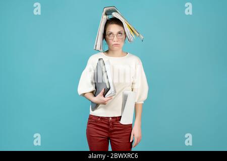 Überlastete Büroangestellte mit einem Ordner mit Dokumenten auf dem Kopf. Hält Dokumente unter seiner Achselhöhle und in ihrer Tasche Stockfoto