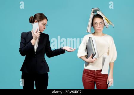 Der Chef wartet auf einen Bericht eines Untergebenen, der schon arbeitssatt ist. Beide Mädchen sind ein Gesicht. Regisseurin Frau neben untergeordneter Frau Stockfoto