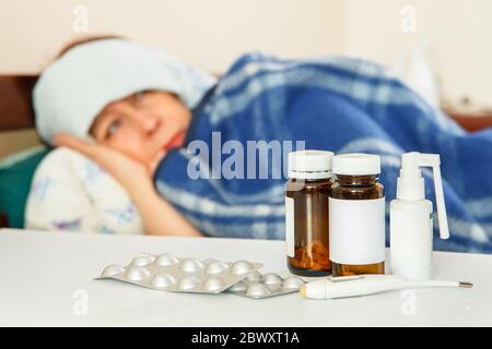 Eine Frau ist krank im Bett neben Medikamenten. Hohe Körpertemperatur. Stockfoto