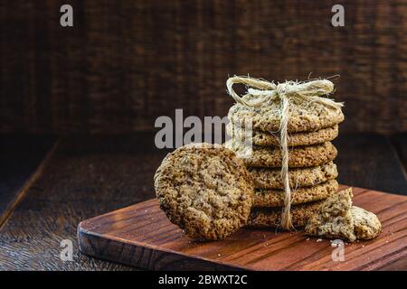 Vollkornkekse mit Getreide, getrockneten Früchten und Schokolade auf altem Holztisch Stockfoto