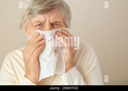 Laufende Nase. Ältere Frau verbringen den ganzen Tag lang, während mit laufender Nase. Eine ältere Frau hat eine verstopfte Nase oder laufende Nase und hat Fieber. Stockfoto