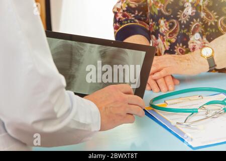 Arzt zeigt ältere Frau MRT-Ergebnisse auf Tablet-Bildschirm Stockfoto