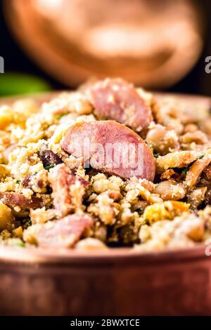 Bohnen mit Schweinefleisch, genannt Tropeiro Bohnen, typische Lebensmittel von Minas Gerais. Gebratene Wurst, Farofa, gebackene Bohnen, Petersilie und Frühlingszwiebeln. Stockfoto