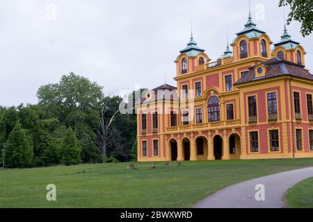 Rot-gelbes Märchenschloss aus dem 18. Jahrhundert 'Schloss Favorite' in Ludwigsburg, Deutschland mit Hirschen auf grüner Wiese Stockfoto