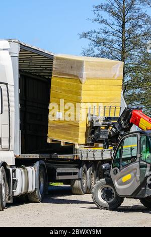 Entladen einer Palette mit Steinwollplatten aus einem LKW mit einem Frontlader Stockfoto