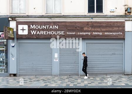 Mountain Warehouse - Mann mit Gesichtsmaske zu Fuß an einem geschlossenen und geschlossenen Shop während der Coronavirus Pandemie Aussperrung, Glasgow, Schottland, Großbritannien Stockfoto