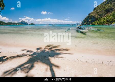 Wunderschöne Landschaft von Corong Corong Strand mit traditionellen Boot und Palmenschatten. El Nido, Palawan, Philippinen Stockfoto