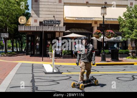 Reston, VA, USA --3. Juni 2020. Ein Mann mit Helm und Jacke fährt auf einem Motorroller im Stadtzentrum von Reston auf der Market Street in Reston. Stockfoto