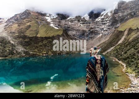 Mann, der an einem wunderschönen blauen See inmitten der Berge in Peru steht. Türkisfarbener See. Stockfoto