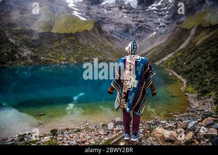 Mann, der an einem wunderschönen blauen See inmitten der Berge in Peru steht. Türkisfarbener See. Stockfoto