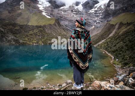 Schöne blonde Frau, die an einem blauen See in der Mitte der Berge in Peru steht. Türkisfarbener See. Stockfoto