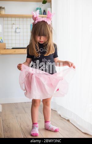 Kleines Mädchen, zu Hause in Verkleidung spielend, trägt ein Ballerina Kostüm mit rosa Tüll Tutu, Socken und Antennen Stockfoto