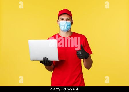 Covid-19, sicheres Einkaufen, Expresslieferung und Auftragsverfolgung Konzept. Schöner junger Kurier, Mitarbeiter in der Transfergesellschaft, bieten sichere Versand von Stockfoto