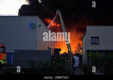 Diez, Deutschland. Juni 2020. Ein Feuerwehrmann löscht einen Großbrand von einer Drehleiter. In einem Gewerbegebiet im Rhein-Lahn-Kreis bricht in einem Unternehmen im Industriepark, das Papierrohstoffe verarbeitet, ein Brand aus. Kredit: Hasan Bratic/dpa/Alamy Live News Stockfoto