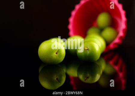 Grüne Pflaumen auf schwarzem Hintergrund Stockfoto
