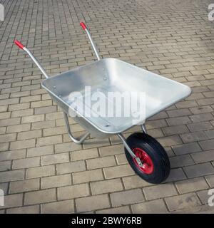 Schubkarre auf Steinboden. Garten ein-Rad-Metallwagen Stockfoto