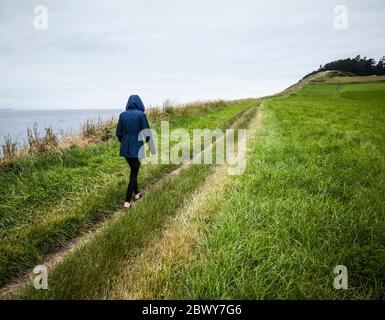 Eine junge Frau, die auf dem Weg nach Ebeys Bluffs, Ebey's Landing National Historical Reserve, Whidbey Island, Washington, USA, läuft. Stockfoto