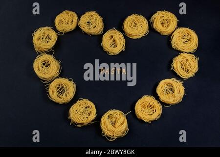 Paste von Buchstaben des Alphabets, auf einem schwarzen Hintergrund mit einer Herzform mit Capelli Pasta. In der Mitte des Herzens befindet sich die Inschrift - PA Stockfoto