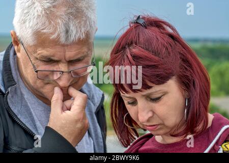 Ein Mann und ein Ehepaar schauen sich die Informationen an, die auf ihrem Handy angekommen sind. Stockfoto