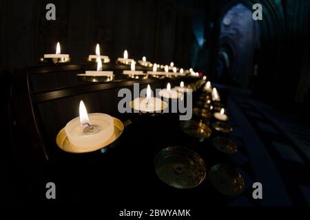 5 Reihen Gebetskerzen laufen von links nach rechts in diesem Weitwinkelfoto aus einer Kathedrale Stockfoto