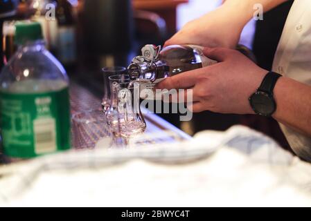 Mann bereitet Getränke an der Bar zu. Nahaufnahme der männlichen Hände Gießen transparent alkoholisches Getränk aus der Flasche. Feier, Geburtstag, Party, Hochzeitskonzept. Stockfoto