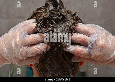 Junge Frau färbt ihr Haar zu Hause. Das Mädchen Färbung ihre Haare in ihrem eigenen Bad. Quarantäne, Haarpflege zu Hause bleiben Konzept. Stockfoto