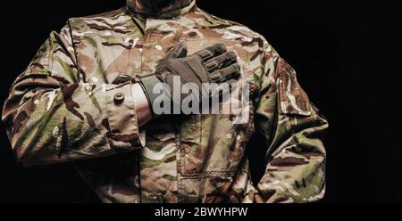 Foto eines Soldaten in multicam Tarntunika mit Hand auf Herz auf schwarzem Hintergrund. Stockfoto