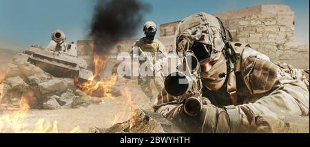 Foto von einem voll ausgestatteten Soldaten legen und Zielgewehr auf Wüste Schlachtfeld mit laufenden Soldaten und Panzer. Stockfoto