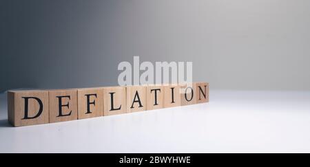 Entflationstext aus Holzwürfeln. Spotlicht im Studio und weißer Hintergrund. Stockfoto